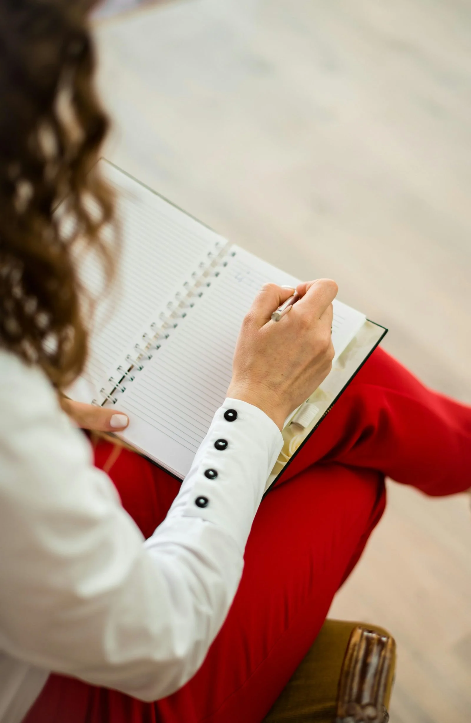 Over-the-shoulder view of a therapist writing in a notebook, planning the week ahead.
