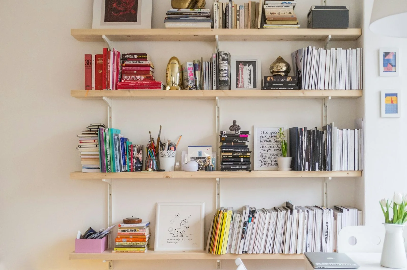 Curated bookshelf with books, magazines, and small art objects.