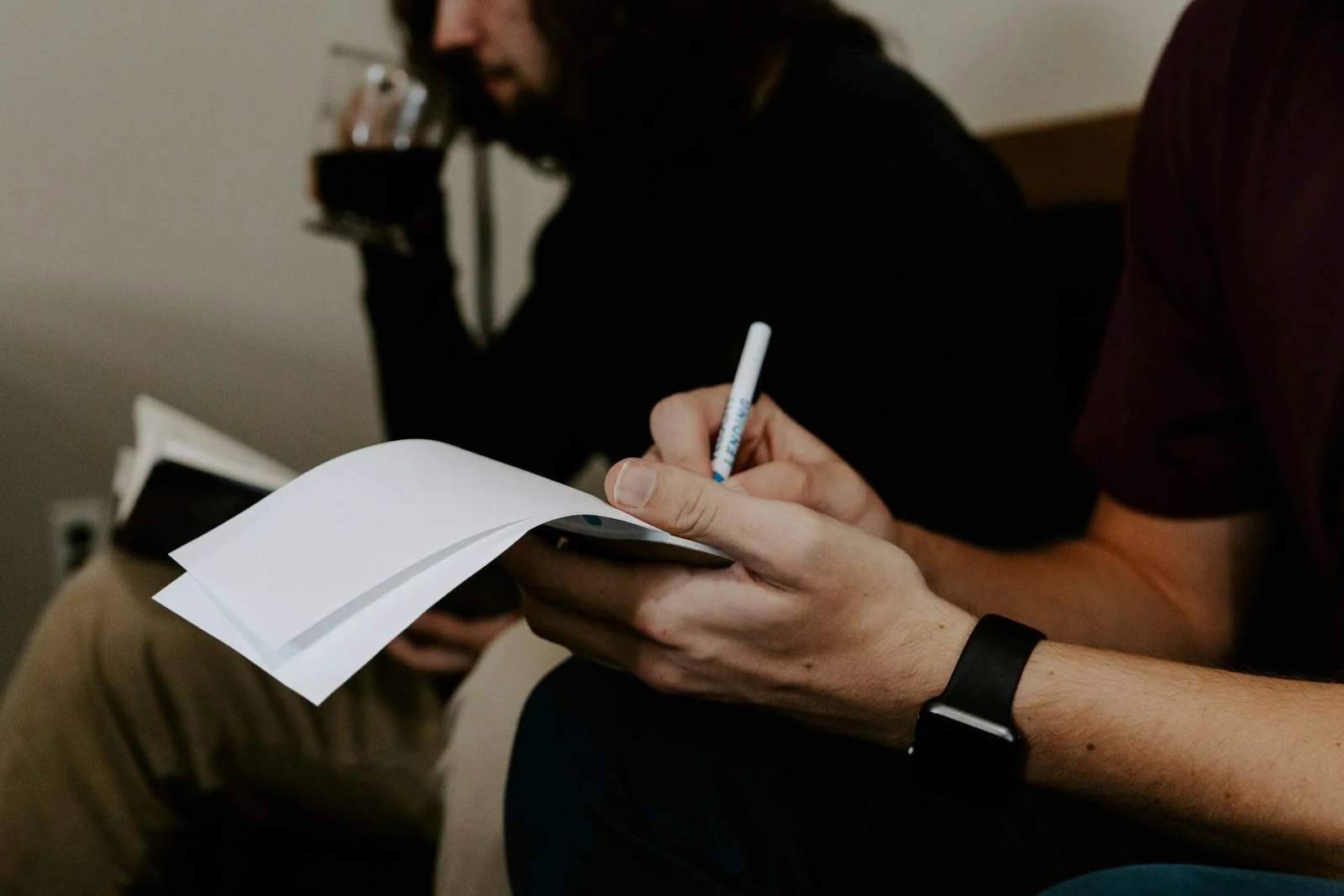 Hands writing on a notepad during a quiet supervisory conversation.