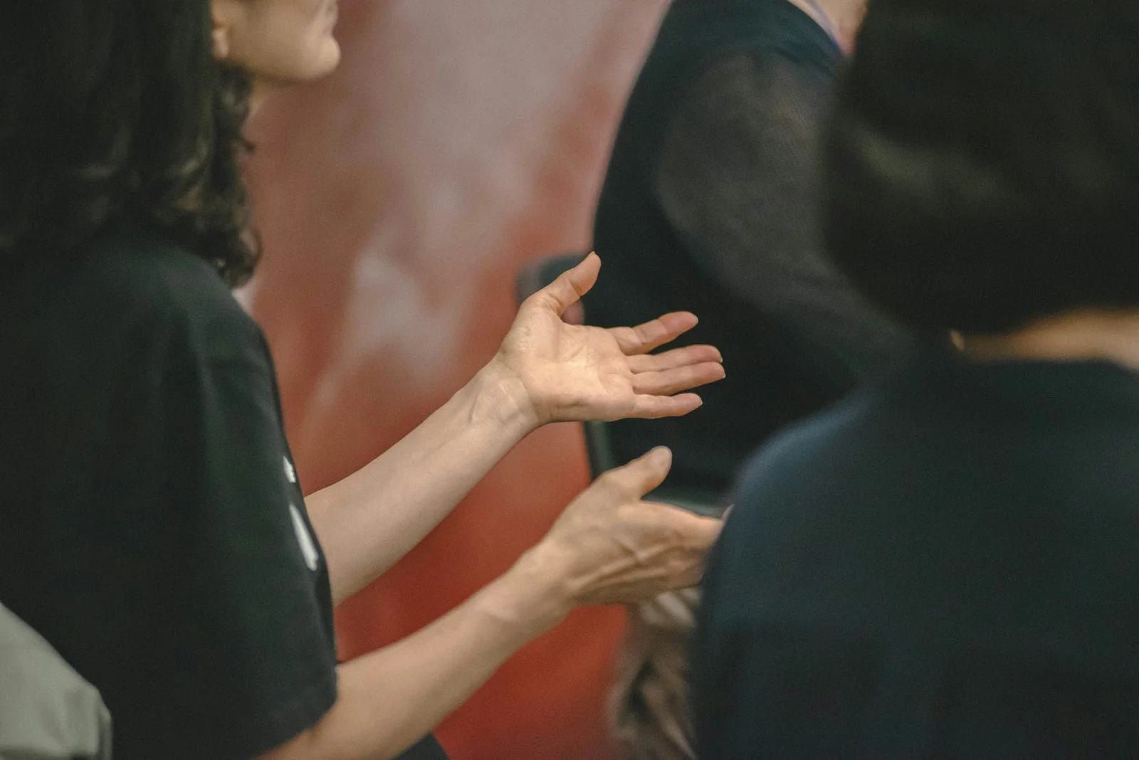Hands gesturing in conversation between two people seated face to face.